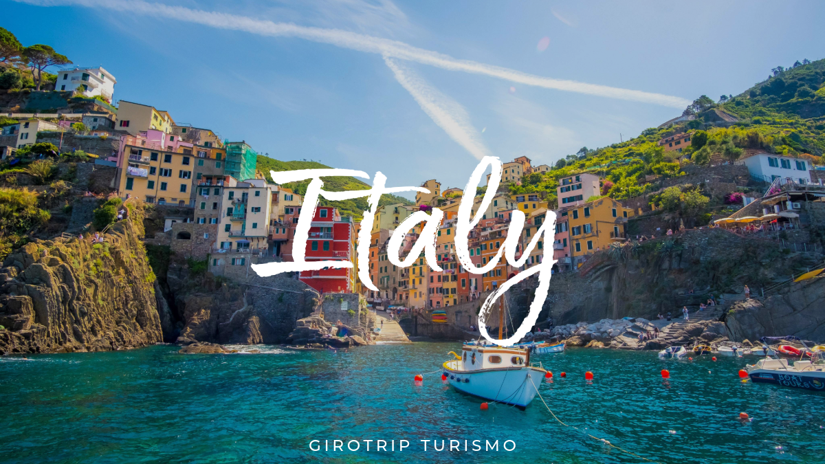 Imagem de capa para o artigo de blog, com vista das coloridas casas de Cinque Terre, na Itália, com um barco no mar. O texto "Italy" e o logo da Girotrip Turismo estão sobre a imagem.
