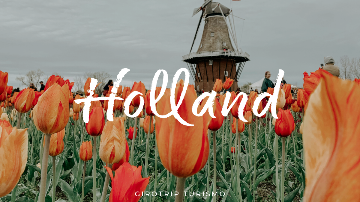 Imagem de capa para o artigo de blog, mostrando um campo de tulipas laranjas com um moinho de vento holandês ao fundo. O texto "Holland" e o logo da Girotrip Turismo estão sobre a imagem.