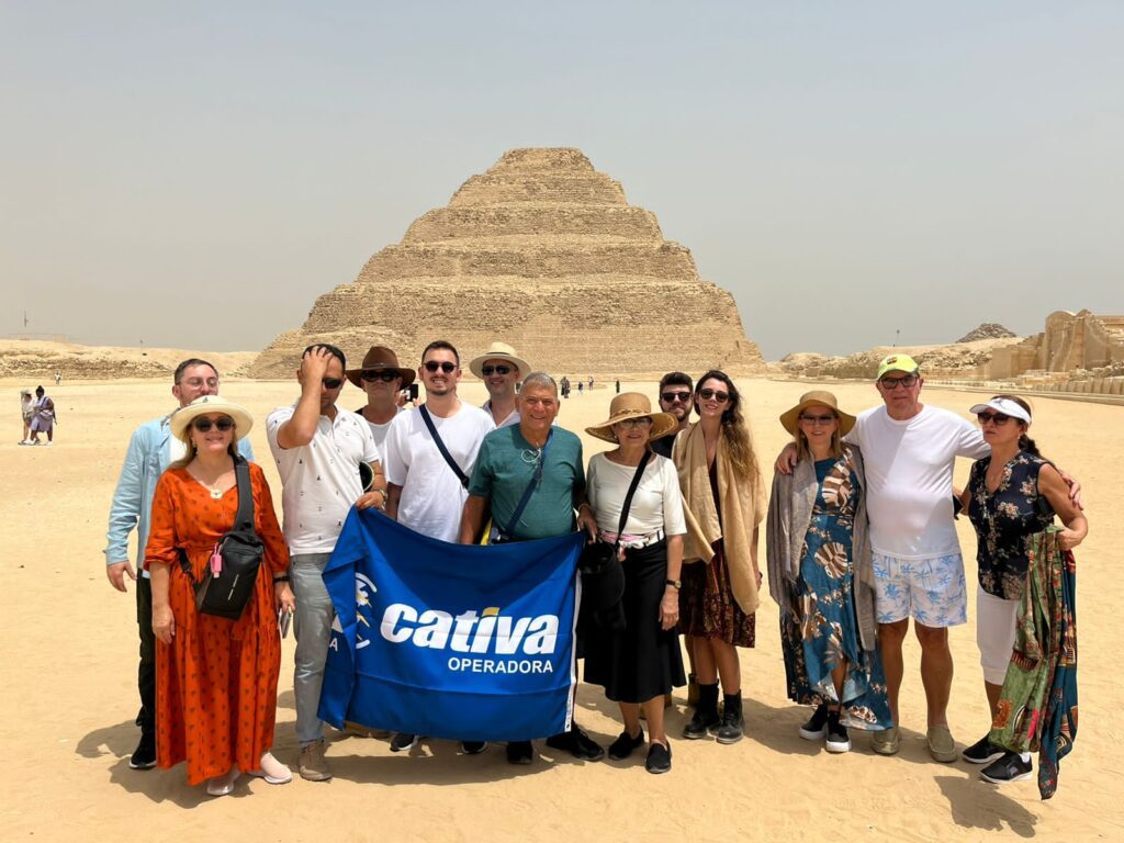 Grupo de viajantes posando em frente à histórica Pirâmide de Degraus de Djoser, em Saqqara, no Egito.
