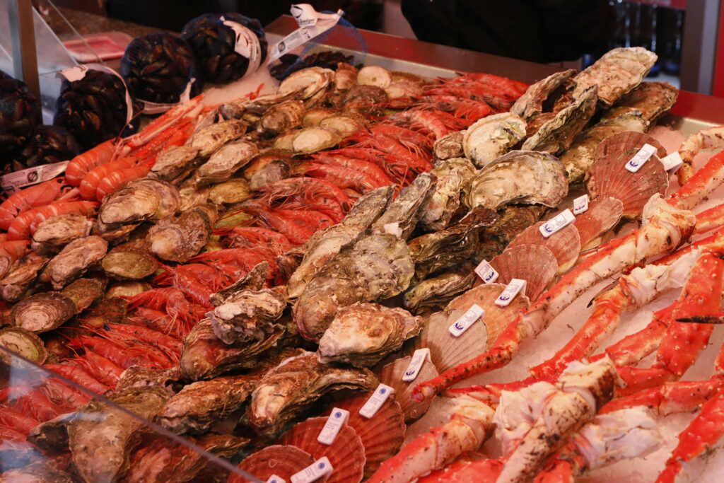 Exposição vibrante de frutos do mar frescos em gelo, incluindo ostras, camarões, vieiras e patas de caranguejo, em um mercado gastronômico.