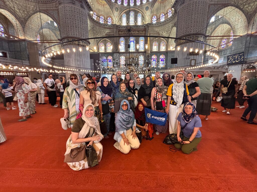 Um grupo 50+ em uma viagem em grupo pela Turquia, posando para uma foto dentro da Mesquita Azul em Istambul.