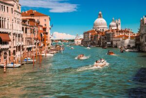 Vista do Grande Canal em Veneza, Itália, com barcos navegando e a arquitetura clássica da Basílica de Santa Maria della Salute ao fundo, uma cena icônica de uma viagem em grupo na Europa.