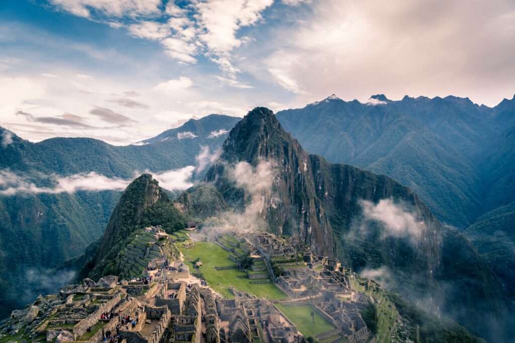 Vista panorâmica da cidadela Inca de Machu Picchu no Peru, com montanhas e névoa ao fundo, um destino imperdível em uma viagem em grupo na América do Sul.

